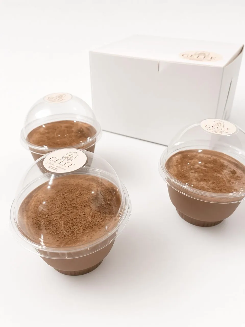Tres gelatinas GELÉE sabor chocolate Abuelita espolvoreadas con cacao, junto a su caja