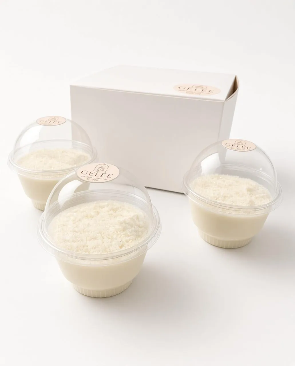 Tres gelatinas GELÉE sabor coco con coco rallado, junto a su caja